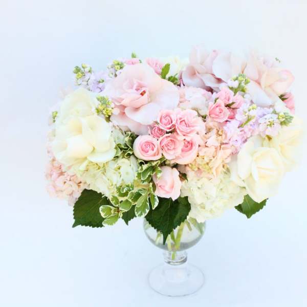 Pastel bouquet of pink and cream flowers in a clear glass vase