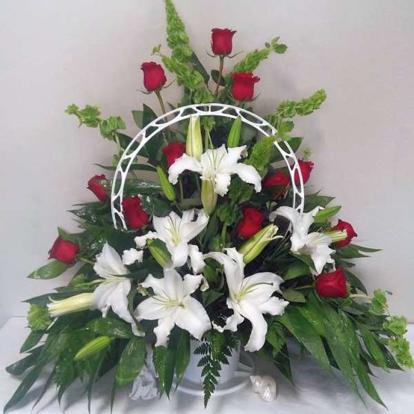 White lilies and red roses arranged in a white basket