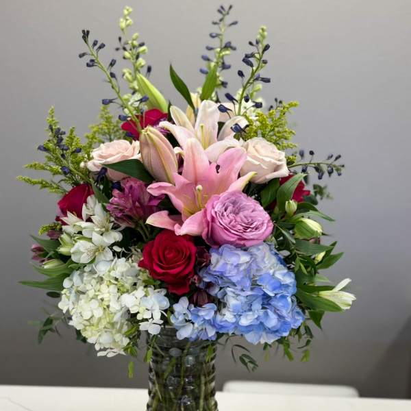 Mixed bouquet of lilies, roses, and hydrangeas in a glass vase