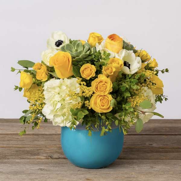 Yellow and white flower arrangement in a blue vase