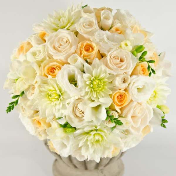 Cream and peach bouquet of roses, dahlias, and calla lilies in a vase
