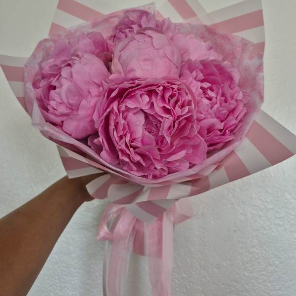 Pink peony bouquet wrapped in striped pink paper with ribbon
