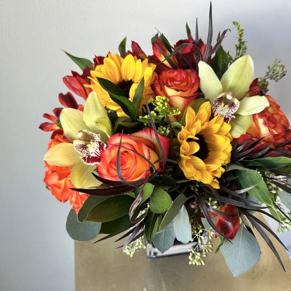 Bouquet with sunflowers, roses, and pale orchids in a vase