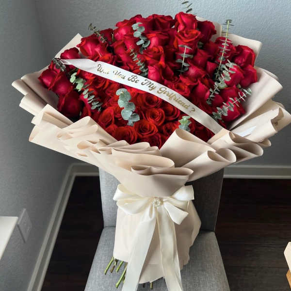 Large bouquet of red roses wrapped in cream paper with a ribbon