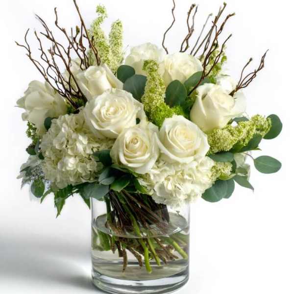 White roses and hydrangeas in a glass vase with branches