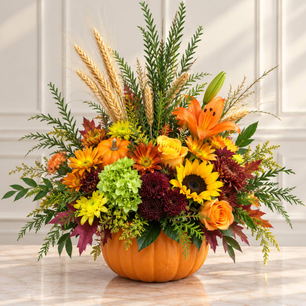 Fall floral arrangement in a pumpkin container with sunflowers and lilies