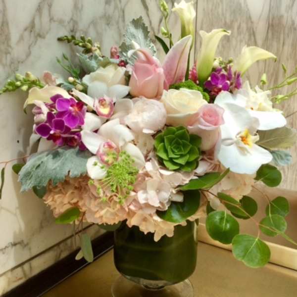 Mixed bouquet of white, pink, and purple flowers in a glass vase
