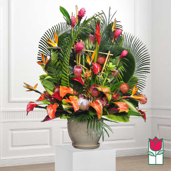 Tropical floral arrangement in a beige urn with orange and pink blooms