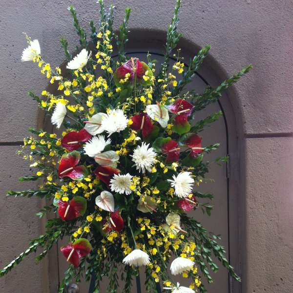 Standing floral spray with red anthuriums, white daisies, and yellow accents