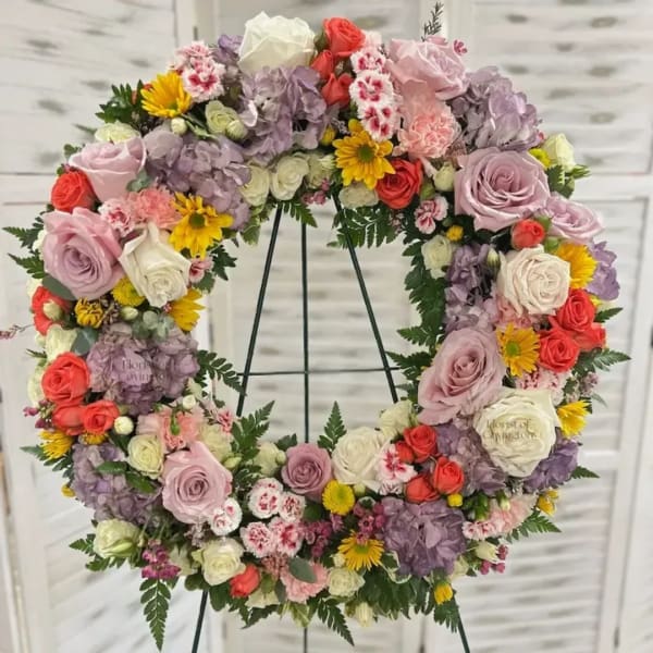 Floral wreath with roses, hydrangeas, and daisies on a stand