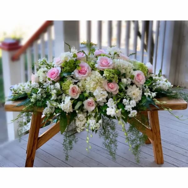Pink and white rose arrangement on a wooden bench