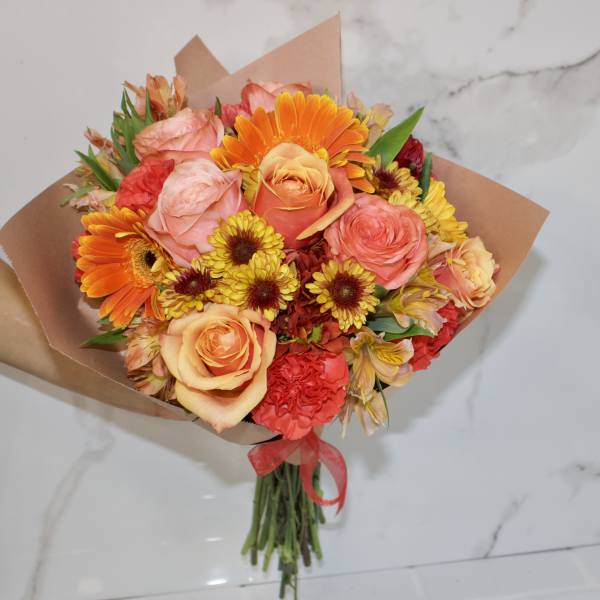 Bouquet of orange, pink, and yellow flowers wrapped in brown paper