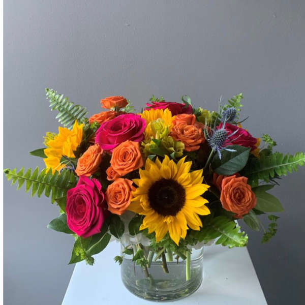Bouquet of bright roses and sunflowers in a clear glass vase