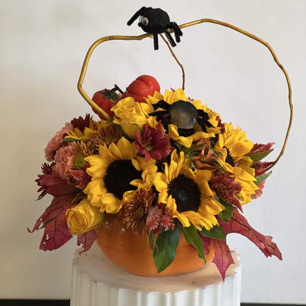 Pumpkin-shaped floral arrangement with sunflowers and black spider decorations