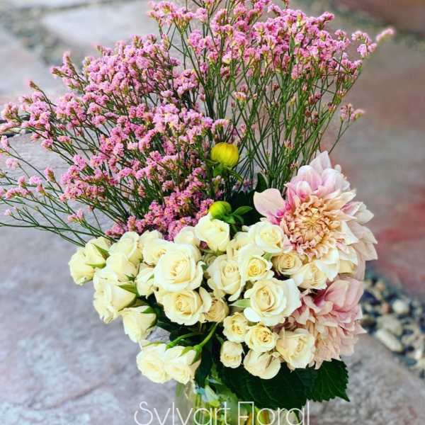 Bouquet of cream roses and pink blooms in a glass vase
