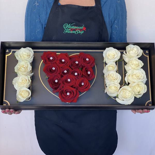 Black tray with red and white roses arranged as "I U"