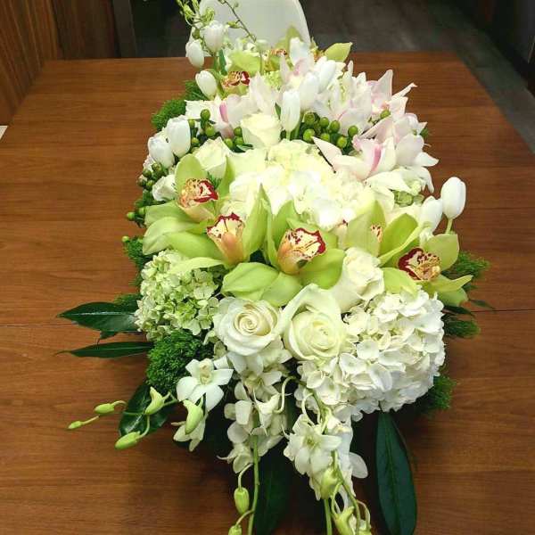 Large white and green floral arrangement with orchids and roses