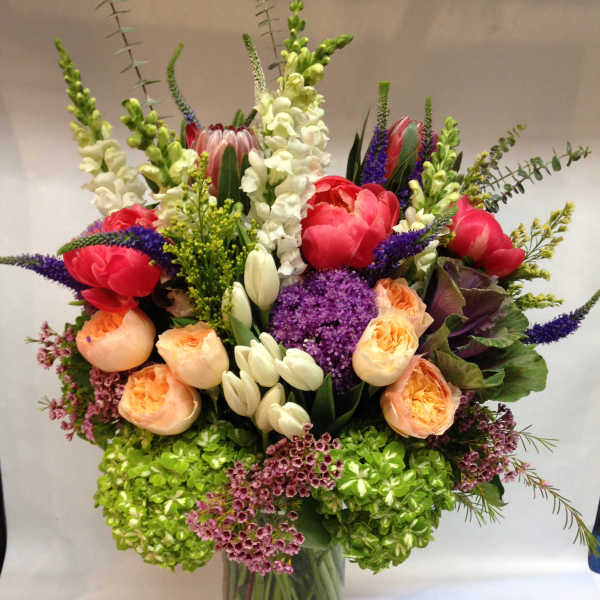 Mixed bouquet in a clear glass vase with pink, peach, white, and purple flowers