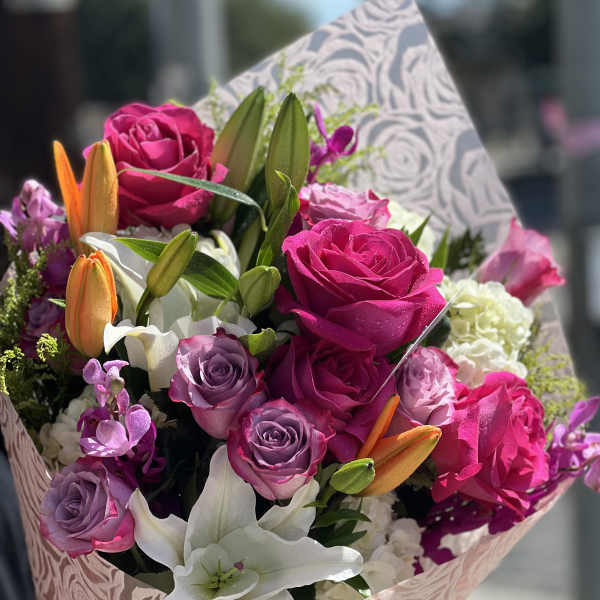 Bouquet of pink and purple roses with white lilies and orange buds
