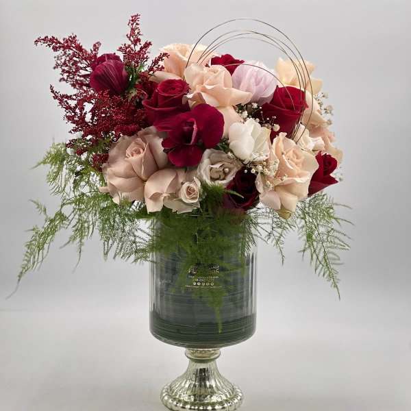 Bouquet of red, blush, and cream roses in a glass vase