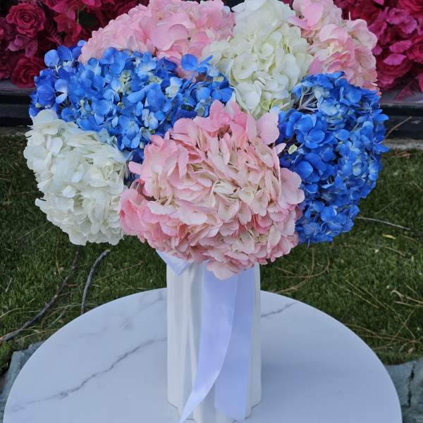 Bouquet of pink, blue, and white hydrangeas in a tall white vase