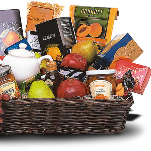 Gift basket with fruit, tea boxes, jam jars, and a white teapot