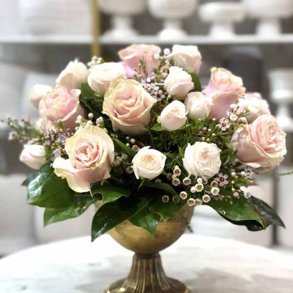 Pink and white roses arranged in a gold pedestal vase