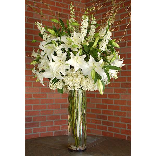 Tall white lily arrangement in a glass vase