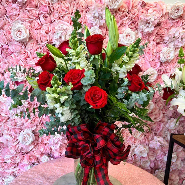 Red roses in a glass vase with a plaid ribbon