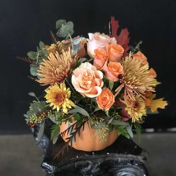 Orange roses and yellow chrysanthemums in a pumpkin-shaped container