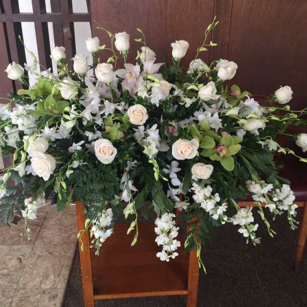 Casket arrangement of pale peach roses and dendrobium orchids