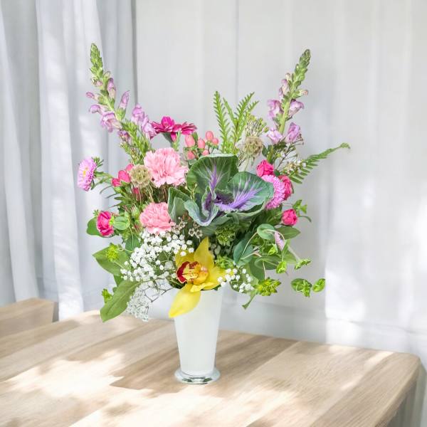 Mixed pink and yellow flower arrangement in a white vase