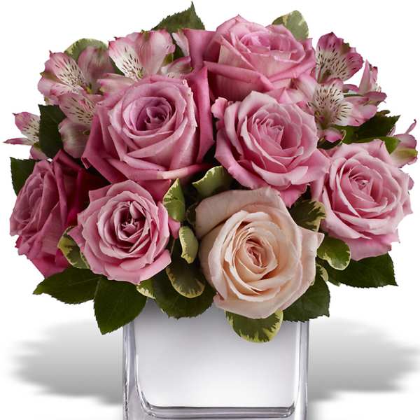 Pink roses and alstroemeria arranged in a clear square vase