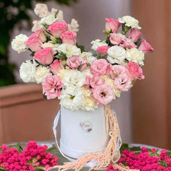Pink and white flower arrangement in a white hatbox with ribbon