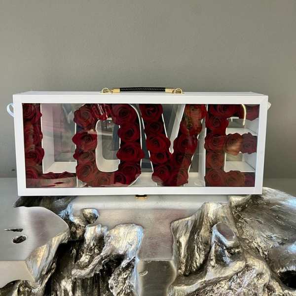 White box with red roses arranged to spell LOVE