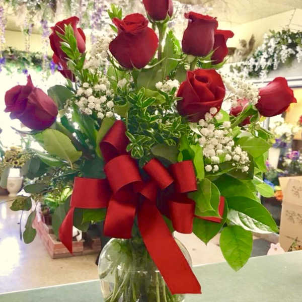 Red roses in a glass vase with a large red ribbon