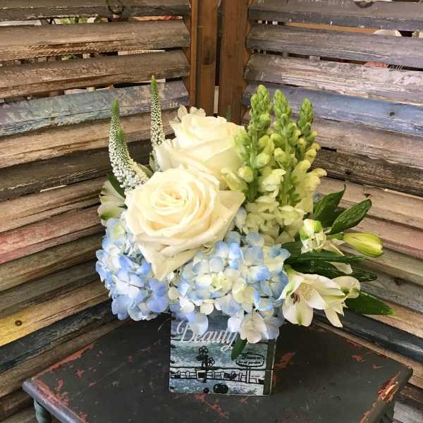 White roses and blue hydrangeas arranged in a decorative box
