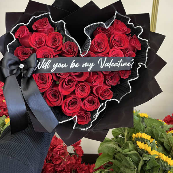 Heart-shaped bouquet of red roses with a black ribbon and Valentine message