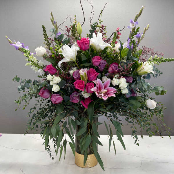 Large mixed bouquet of pink, white, and purple flowers in a gold vase