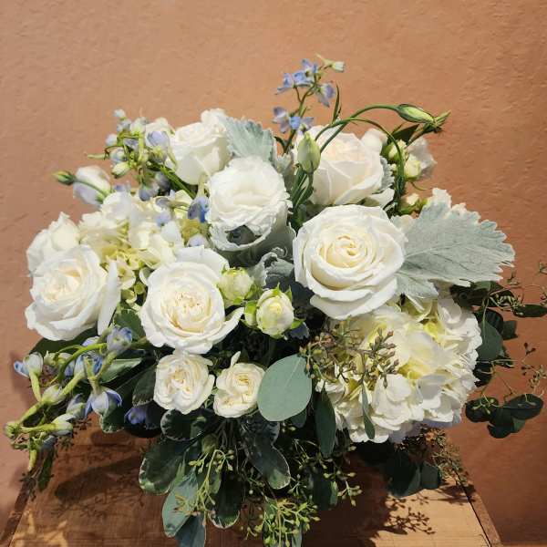 White rose bouquet with pale blue accents and greenery
