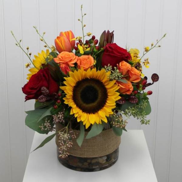 Sunflower and rose arrangement in a glass vase wrapped with burlap