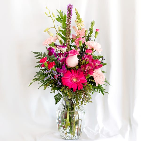 Mixed pink and purple flower arrangement in a clear glass vase