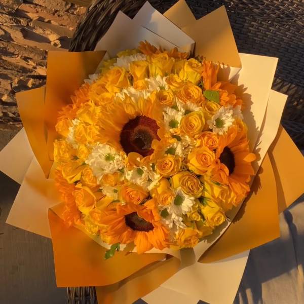 Orange bouquet with sunflowers, yellow roses, and white daisies in paper wrap