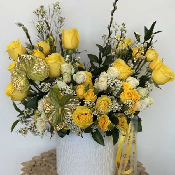 Yellow and white rose arrangement in a white textured vase