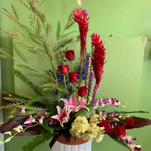 Tall floral arrangement with red roses, pink lilies, and purple orchids in a vase
