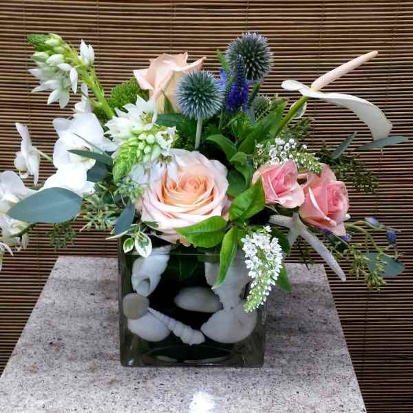 Mixed bouquet with pink roses and white flowers in a square glass vase