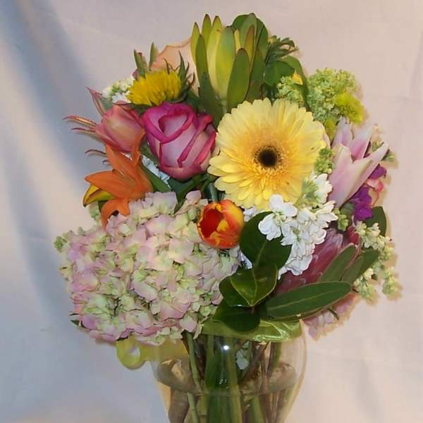 Mixed bouquet in a clear glass vase with pink, yellow, and orange blooms
