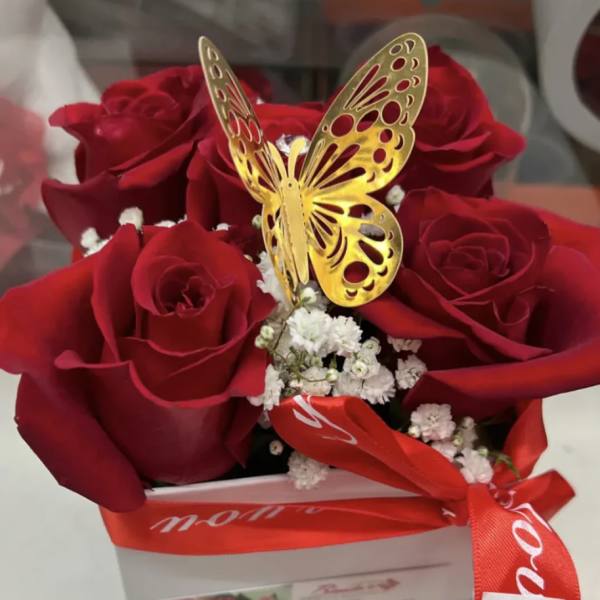 Red roses in a white box with a gold butterfly topper