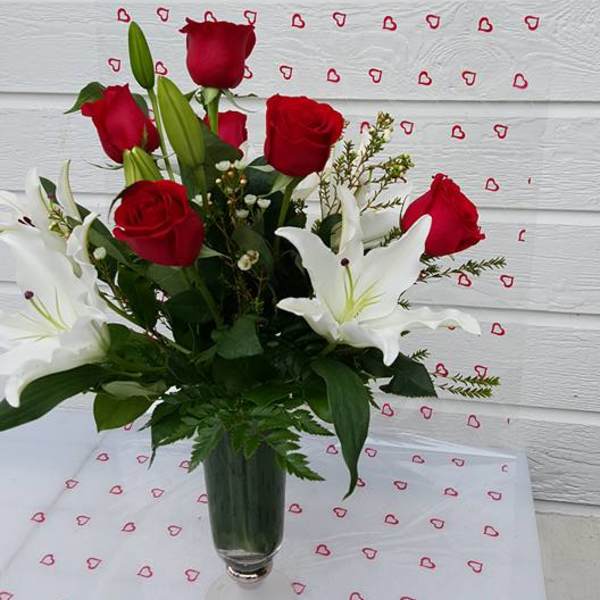 Red roses and white lilies arranged in a clear glass vase