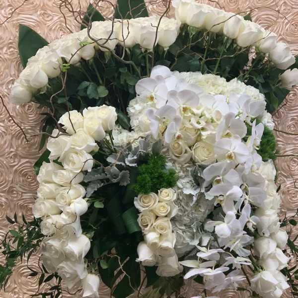 White floral arrangement in a clear vase with roses and orchids